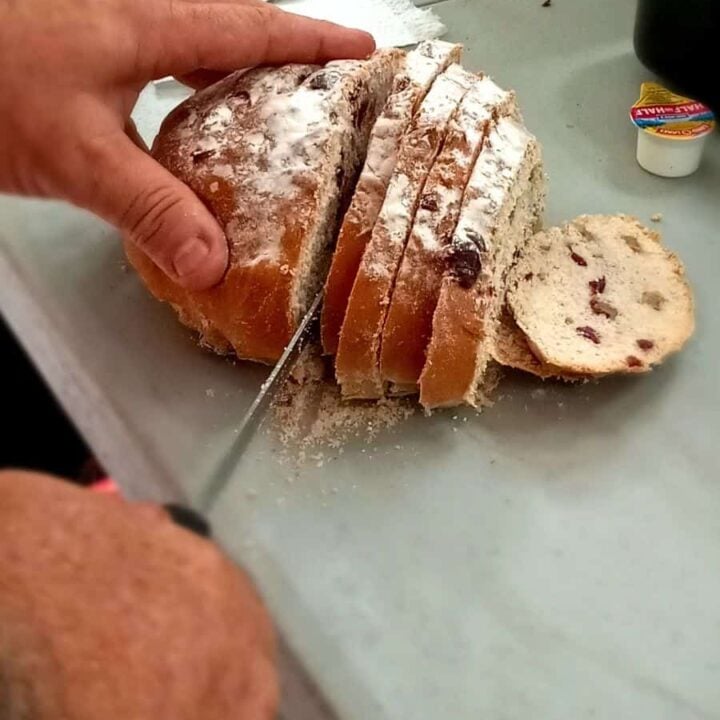 Thick slice of cranberry walnut artisan bread served with butter for breakfast.