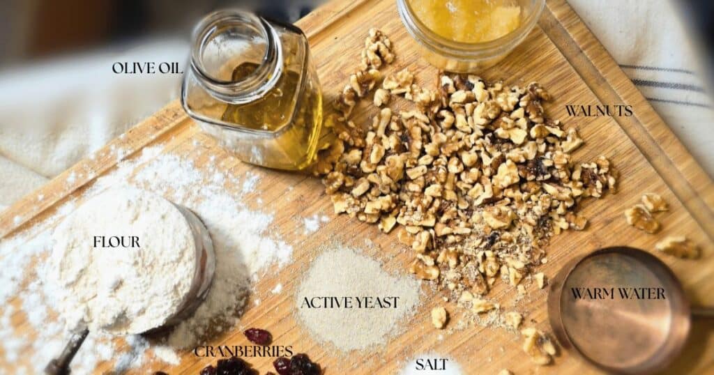 Ingredients for homemade cranberry walnut artisan bread including flour, yeast, dried cranberries, walnuts, and water.