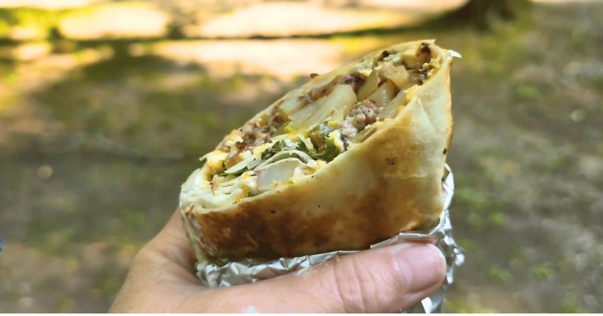 THIS IS AN IMAGE OF A BREAKFAST BURRITO OUT CAMPING IN A HAND