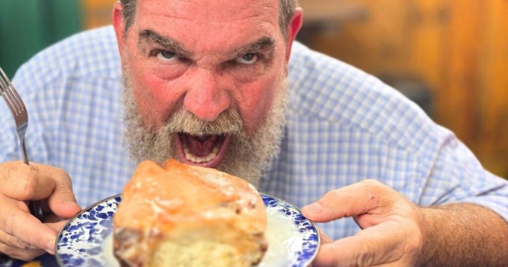 Close-up of fluffy homemade cinnamon rolls with creamy icing dripping between layers.