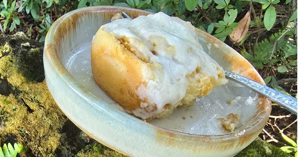 Close-up of fluffy homemade cinnamon rolls with creamy icing dripping between layers.