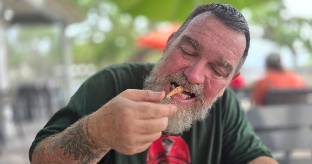 AUNT KATE'S RESTAURANT THIS IS AN IMAGE OF A MAN EATING BOILED SHRIMP