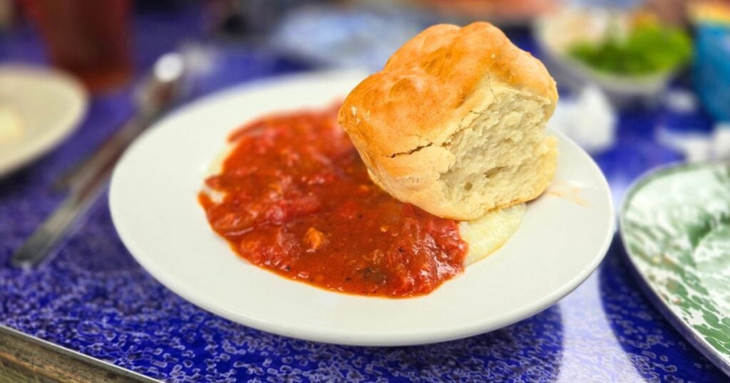 THIS ISA N IMAGE OF THE GRITS AND TOMATO GRAVY WITH A GIANT FLUFFY BISCUIT