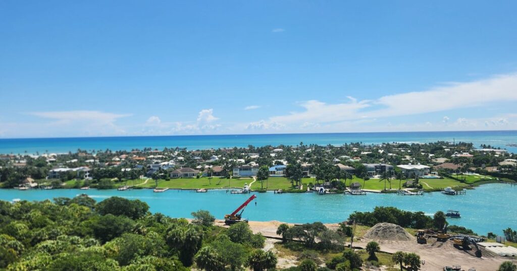 Cliffside luxury homes on waterfront with boats and lush greenery in a coastal neighborhood.