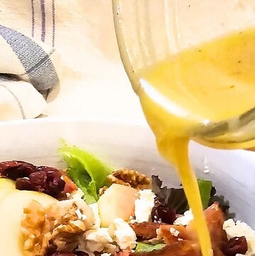 Florida Sunshine Vinaigrette is being drizzled over a fresh green salad.