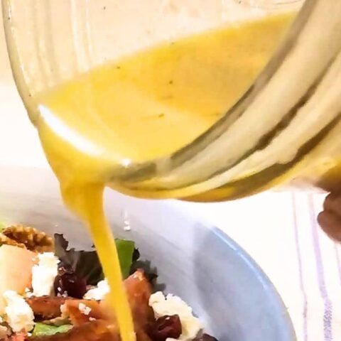 Florida Sunshine Vinaigrette is being drizzled over a fresh green salad.