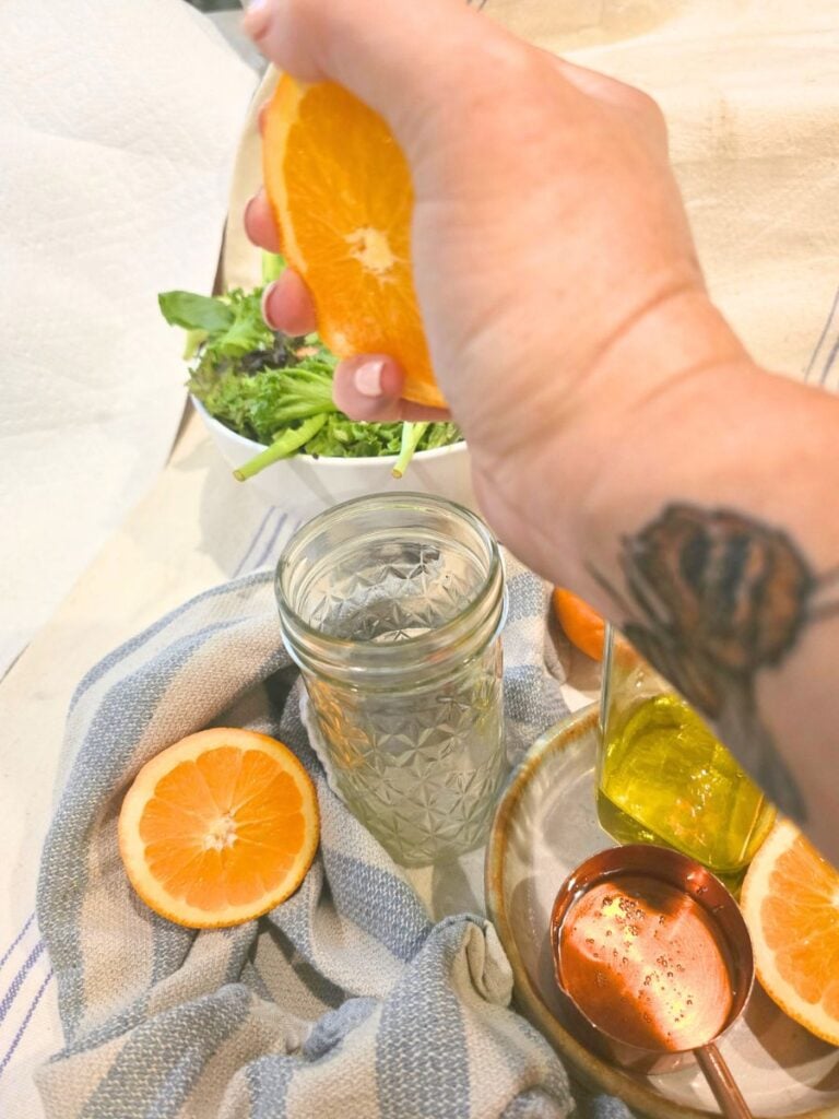Fresh orange being squeezed into a mason jar for homemade citrus vinaigrette.