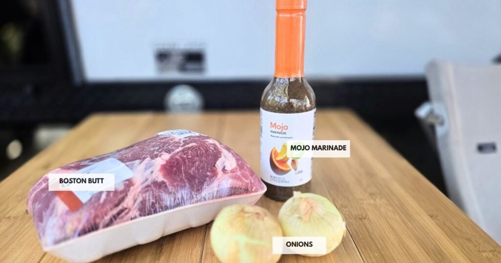 All ingredients for Crockpot Mojo Pork recipe: pork shoulder, sliced onions, and bottled mojo marinade ready for slow cooking.