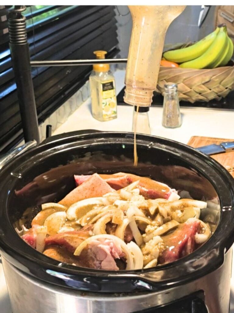 Pouring zesty orange-lime mojo marinade over pork in the crockpot