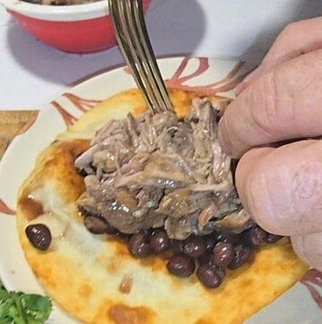 Juicy crockpot mojo pork piled on a soft tortilla ready for tacos or wraps