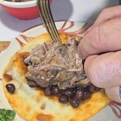 Juicy crockpot mojo pork piled on a soft tortilla ready for tacos or wraps