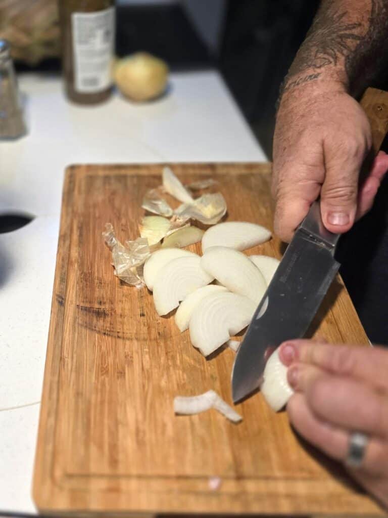 Thinly slicing fresh onions to cook alongside the mojo pork