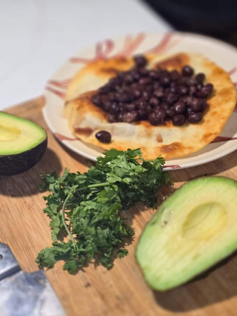 Assembling breakfast pork tostadas with layers of crispy tortilla, mojo pork, egg, cheese, and fresh toppings