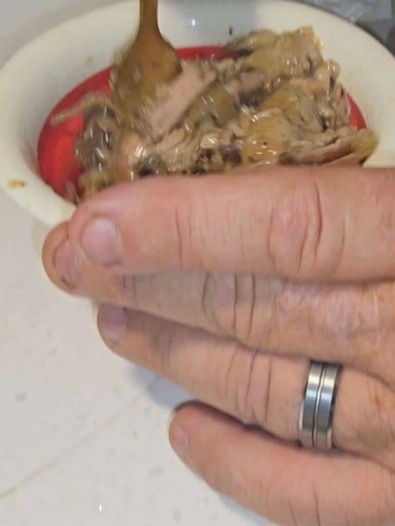 Reheating leftover mojo pork in a skillet for easy breakfast tostadas at the campsite