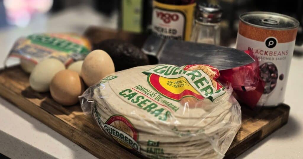 Ingredients for breakfast pork tostadas including leftover mojo pork, eggs, tortillas, avocado, cheese, and cilantro