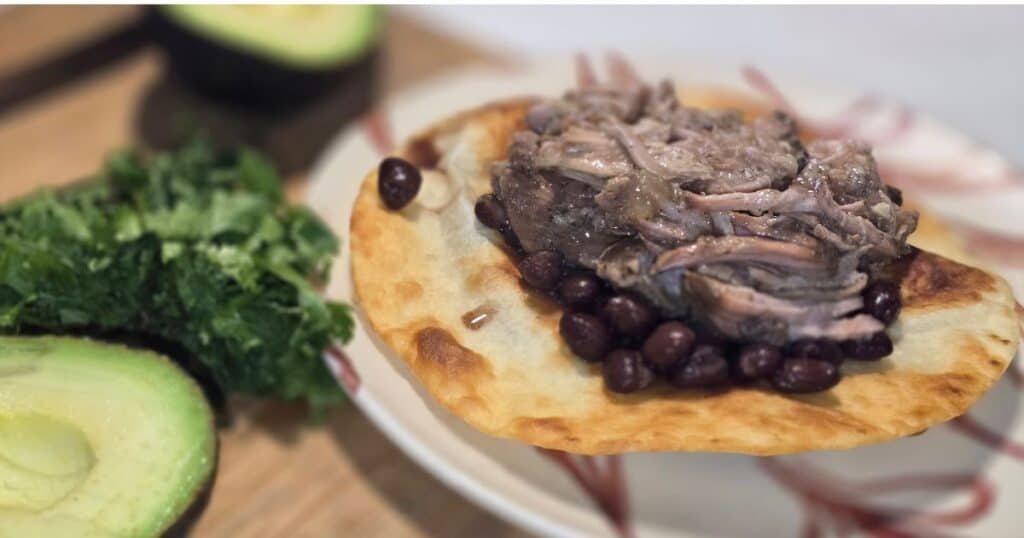 Shredded mojo pork piled on a crispy tostada for an easy camping breakfast recipe